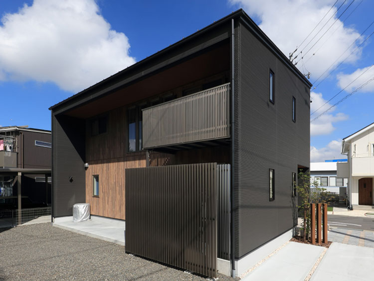 黒い外壁にワンポイントの木目が入ったキューブ型住宅